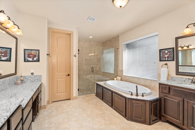 bathroom with a bath, visible vents, a shower stall, two vanities, and a sink