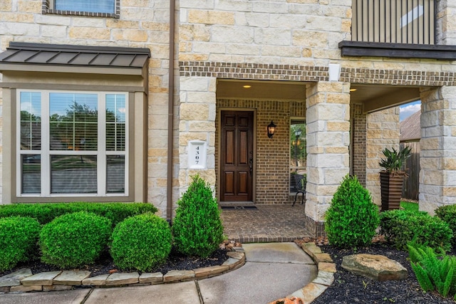 entrance to property with covered porch and stone siding