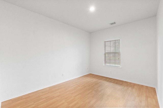 spare room with visible vents, light wood-style flooring, and baseboards
