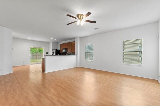 unfurnished living room with plenty of natural light, ceiling fan, light wood finished floors, and visible vents