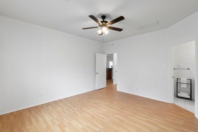 spare room with light wood-type flooring, a ceiling fan, and baseboards
