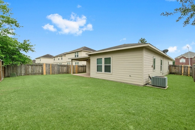 rear view of property with a fenced backyard, a yard, and central AC