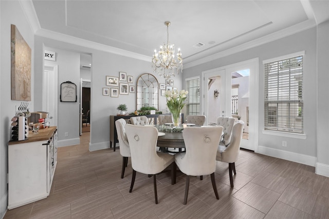 dining room with an inviting chandelier, a raised ceiling, baseboards, and a wealth of natural light
