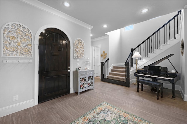 foyer entrance with crown molding, recessed lighting, baseboards, and stairway