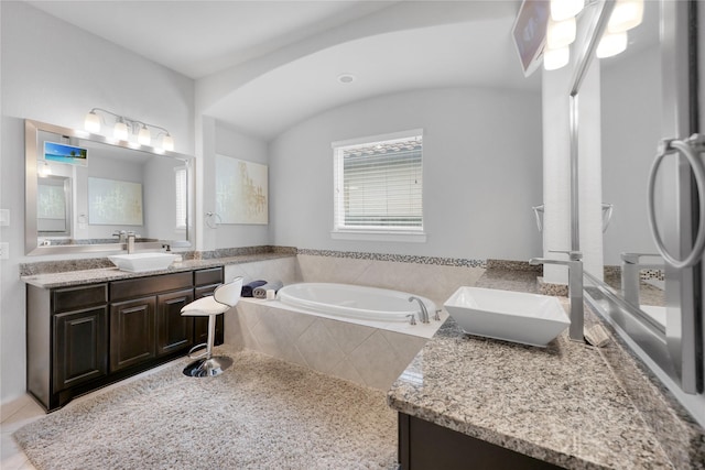 bathroom with tile patterned floors, a garden tub, and vanity