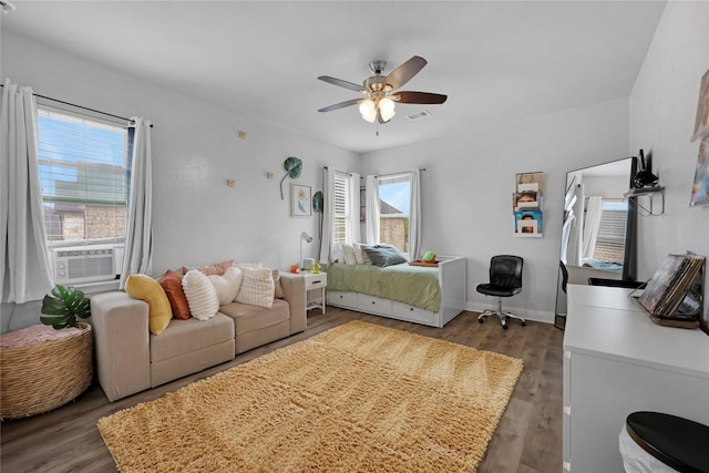 bedroom featuring wood finished floors, cooling unit, and multiple windows