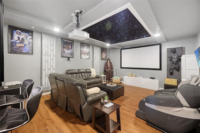 home theater with recessed lighting, wood finished floors, and a tray ceiling