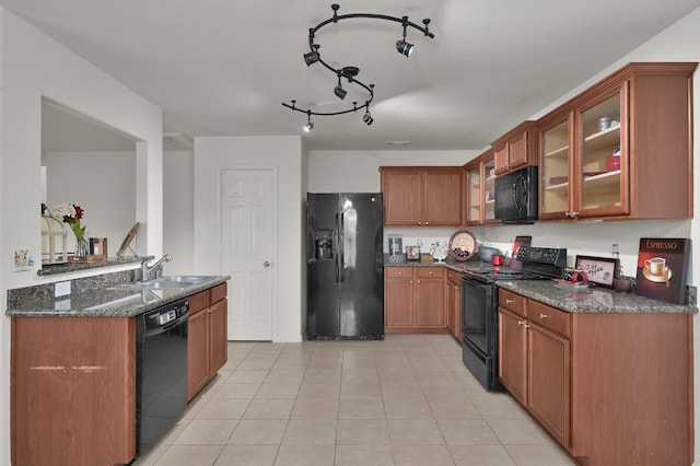 kitchen with black appliances, a sink, dark stone countertops, light tile patterned floors, and glass insert cabinets