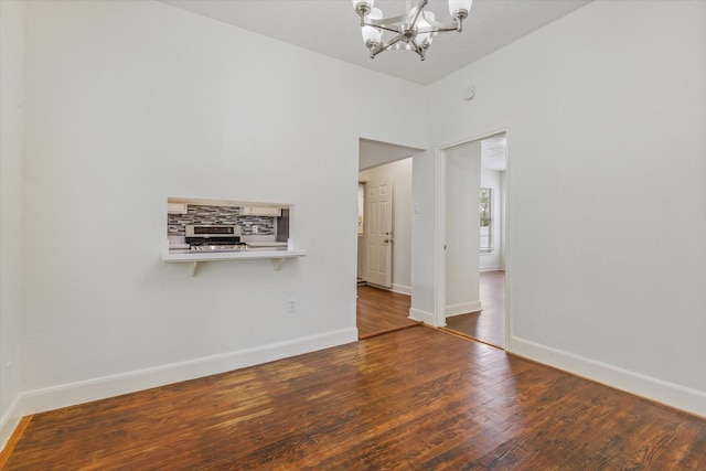 spare room featuring baseboards, a chandelier, and wood finished floors