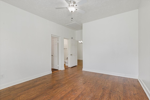 unfurnished room featuring baseboards, a ceiling fan, attic access, and wood finished floors