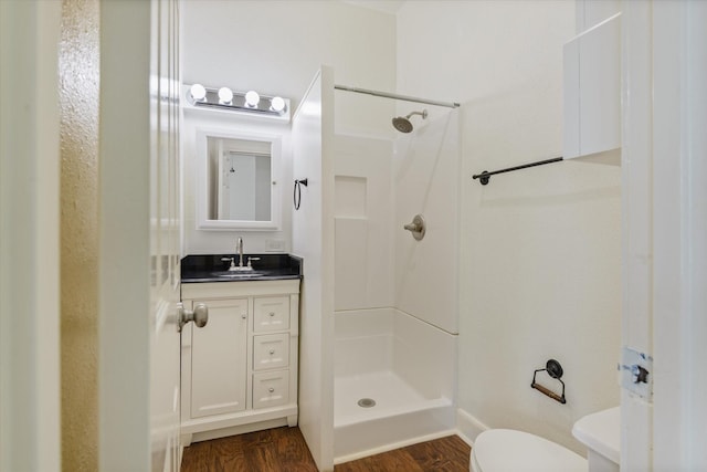 bathroom with a stall shower, wood finished floors, vanity, baseboards, and toilet