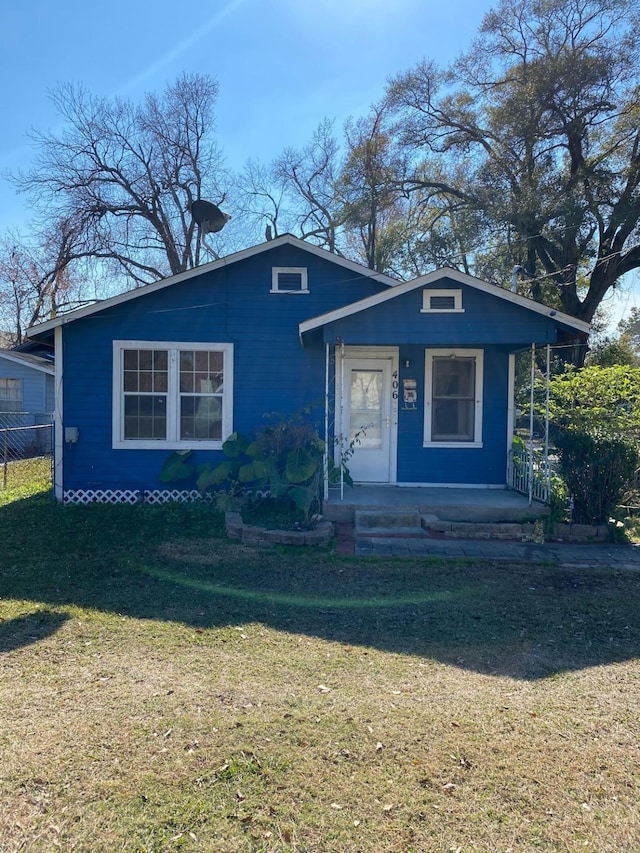 bungalow-style home featuring a front lawn, fence, and covered porch