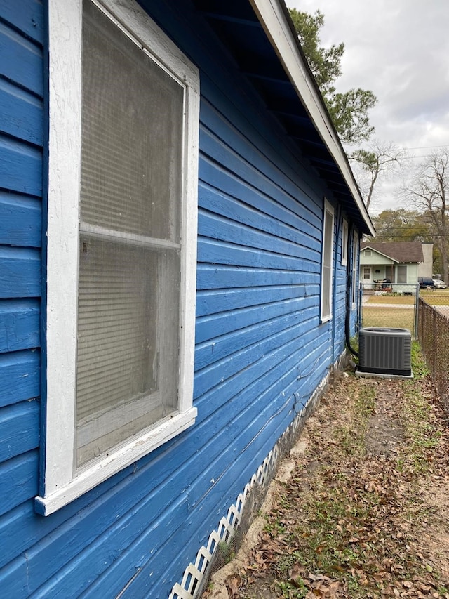view of side of home with central AC and fence