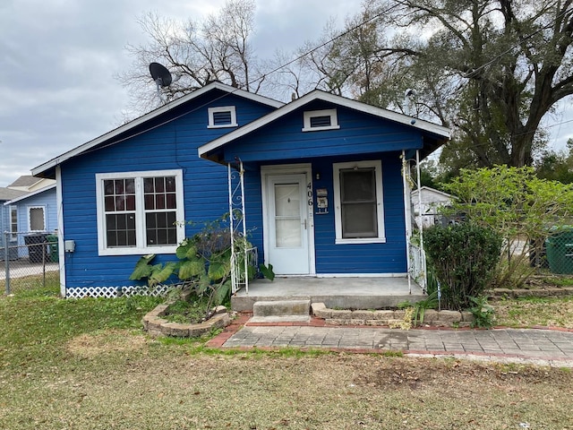 bungalow-style house featuring fence, a porch, and a front lawn