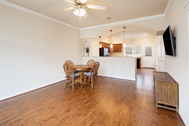 dining space with arched walkways, visible vents, ornamental molding, and dark wood finished floors