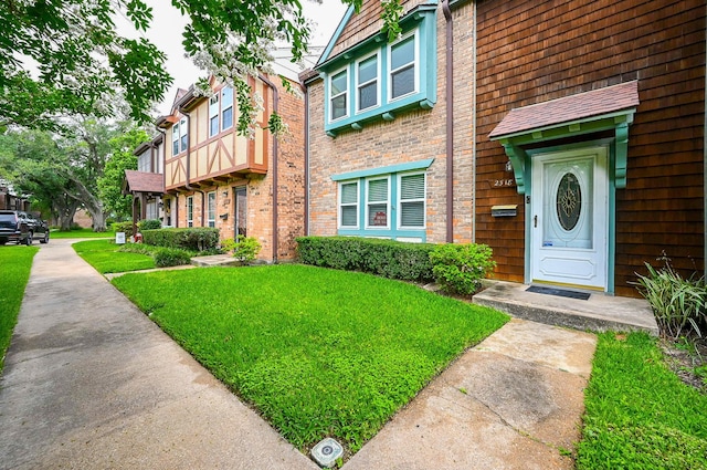 view of exterior entry featuring a yard and brick siding