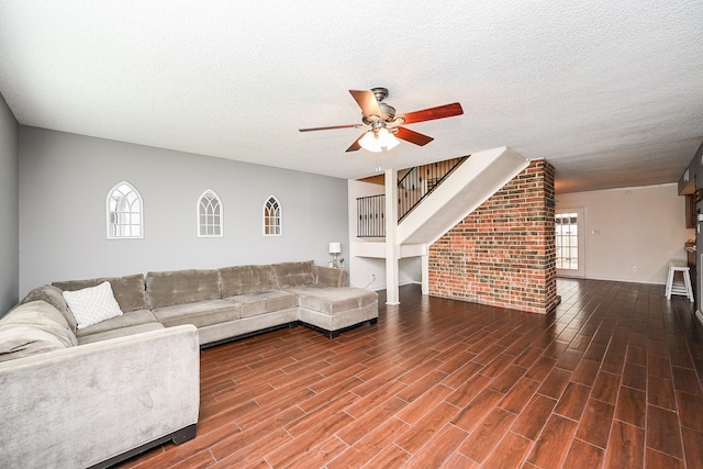living area featuring wood finished floors, baseboards, ceiling fan, stairway, and a textured ceiling
