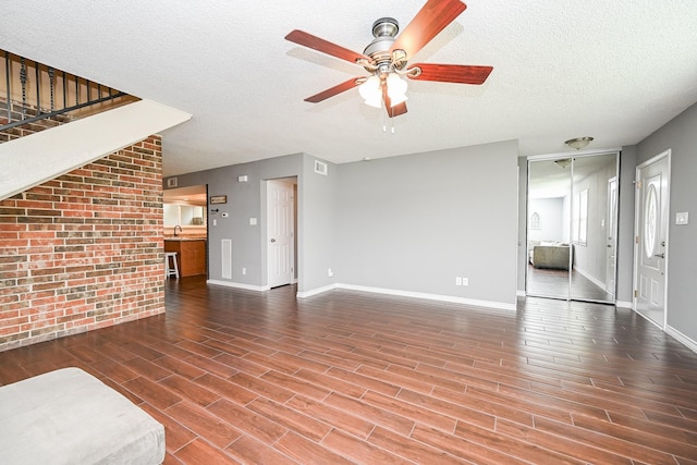 unfurnished living room with ceiling fan, a textured ceiling, visible vents, wood finished floors, and baseboards