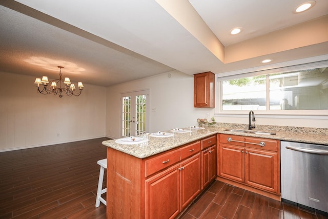 kitchen featuring a peninsula, dark wood finished floors, a sink, and dishwasher
