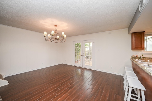 unfurnished dining area featuring dark wood-type flooring, a textured ceiling, a chandelier, and visible vents