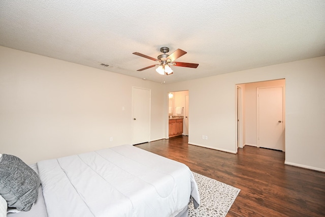 bedroom featuring visible vents, dark wood-style flooring, ensuite bathroom, baseboards, and a ceiling fan