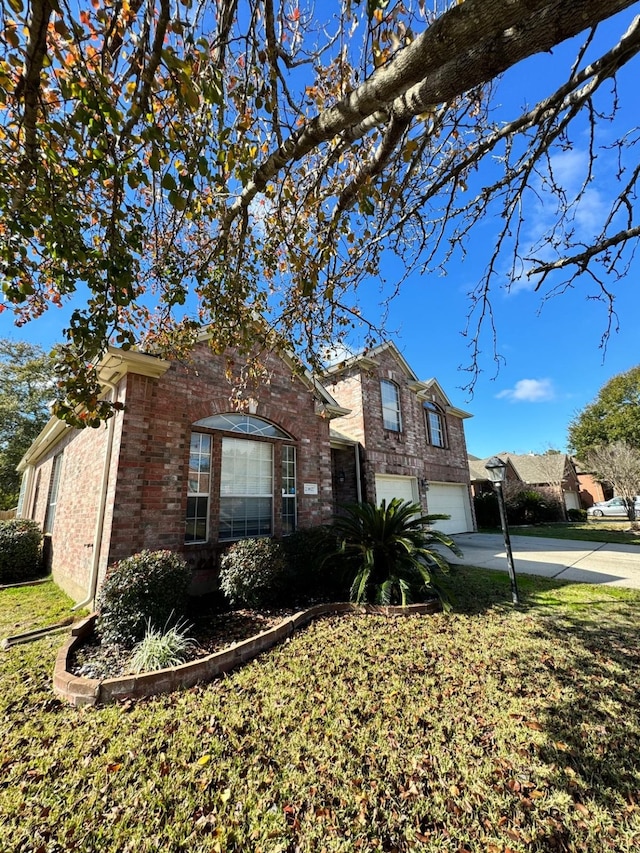 split level home with an attached garage, concrete driveway, and brick siding