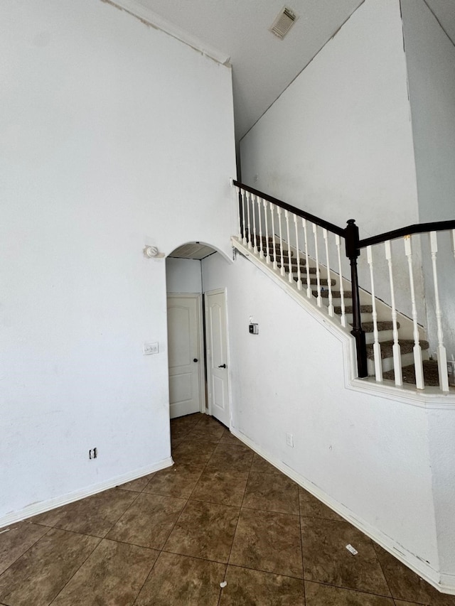 stairway featuring arched walkways, baseboards, tile patterned flooring, and visible vents