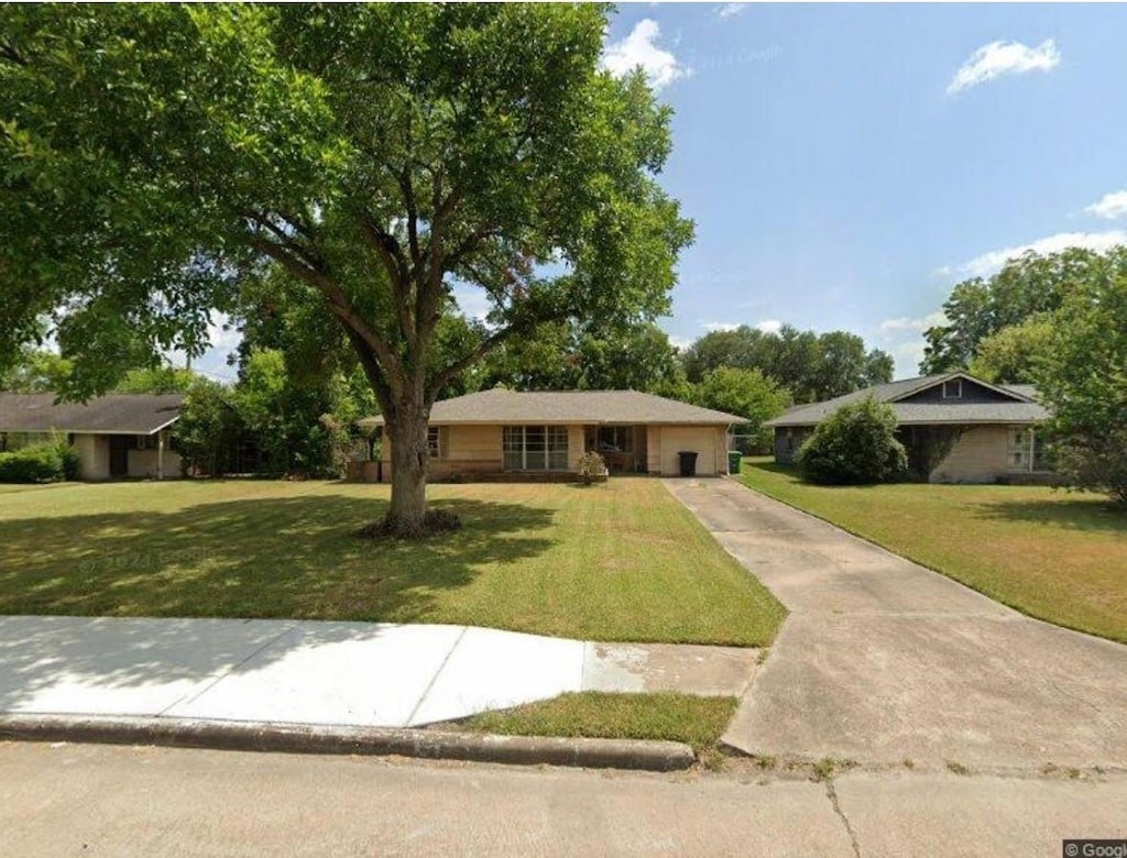 ranch-style house featuring driveway, a front yard, and a garage