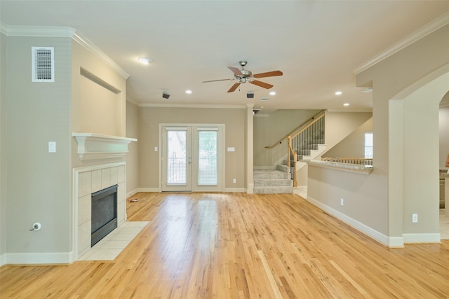 unfurnished living room featuring light wood finished floors, a tiled fireplace, a ceiling fan, baseboards, and visible vents