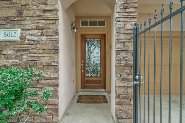 property entrance with a gate, visible vents, and stone siding