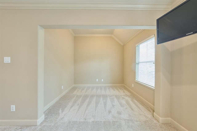 carpeted spare room with crown molding, baseboards, and vaulted ceiling