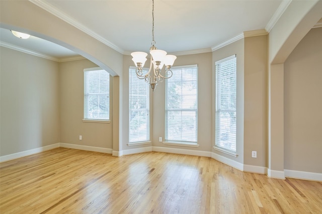 unfurnished dining area featuring crown molding, arched walkways, wood finished floors, baseboards, and a chandelier