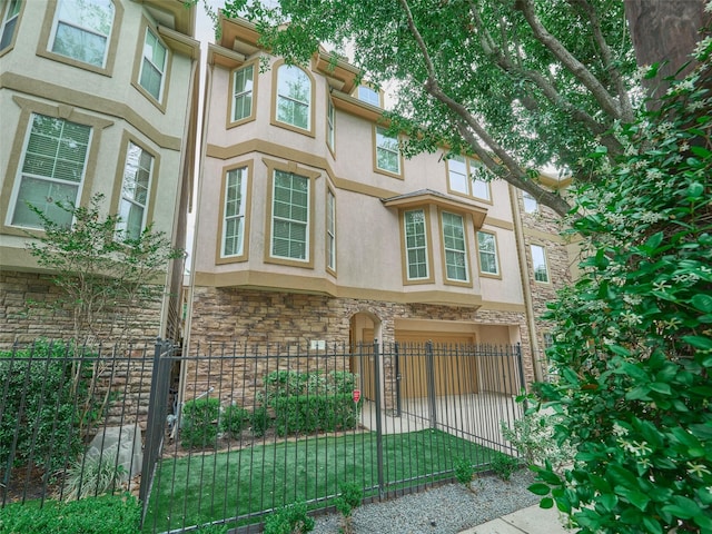 view of home's exterior featuring a garage, stucco siding, a fenced front yard, and stone siding