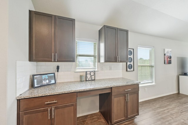 kitchen with light stone counters, decorative backsplash, and wood finished floors