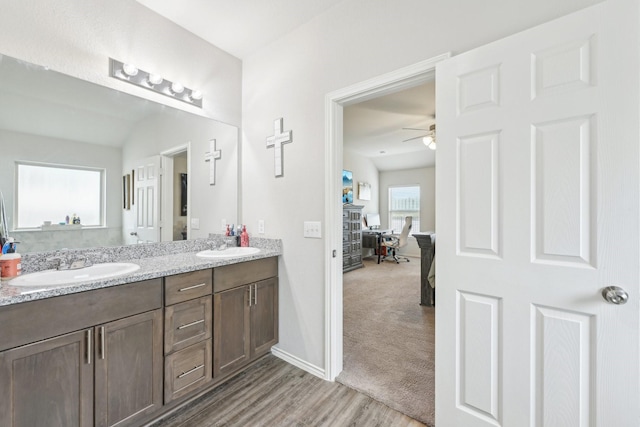 full bath featuring double vanity, a ceiling fan, a sink, and wood finished floors