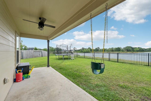 view of yard with ceiling fan, a trampoline, a patio, a fenced backyard, and a water view
