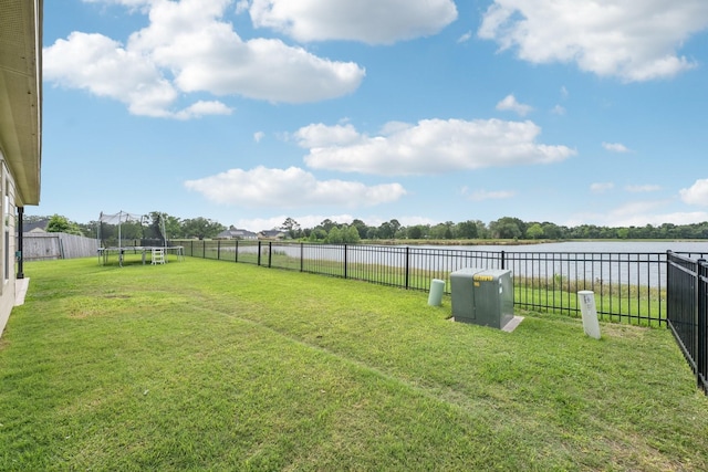 view of yard featuring a fenced backyard, a trampoline, and a water view
