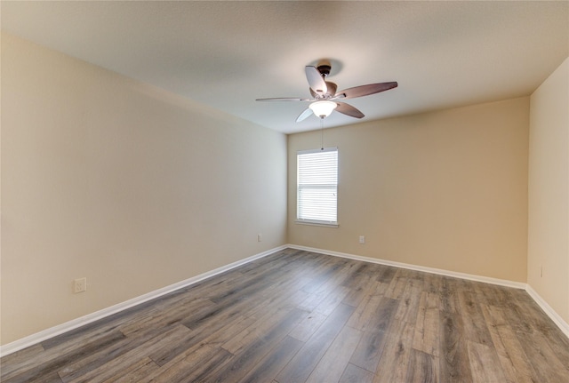 empty room featuring baseboards, a ceiling fan, and dark wood-style floors