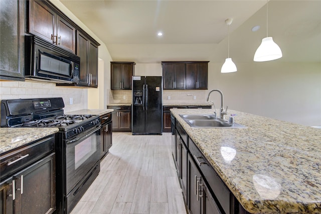 kitchen with pendant lighting, a sink, light wood finished floors, backsplash, and black appliances