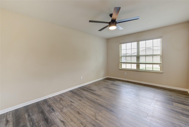 spare room with baseboards, a ceiling fan, and dark wood-style floors