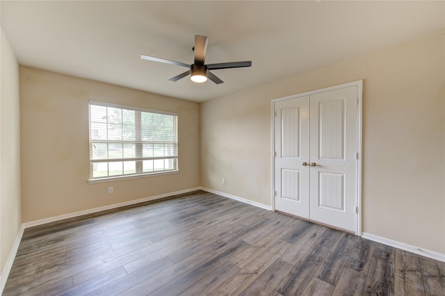 unfurnished bedroom with baseboards, ceiling fan, a closet, and dark wood-type flooring
