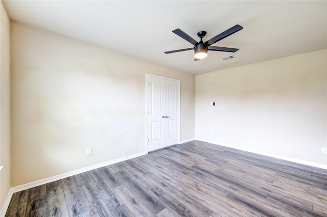 empty room featuring visible vents, a ceiling fan, baseboards, and wood finished floors