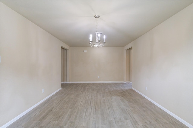unfurnished room with baseboards, an inviting chandelier, and light wood finished floors