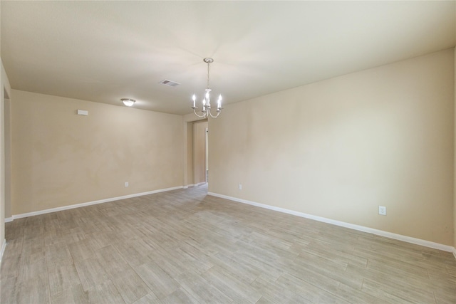 empty room featuring baseboards, visible vents, light wood-style flooring, and a chandelier