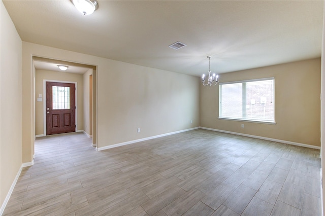 unfurnished room featuring visible vents, baseboards, an inviting chandelier, and light wood finished floors