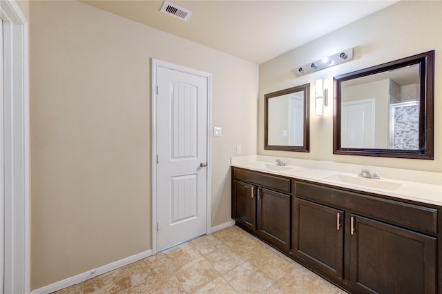 bathroom with double vanity, baseboards, visible vents, and a sink