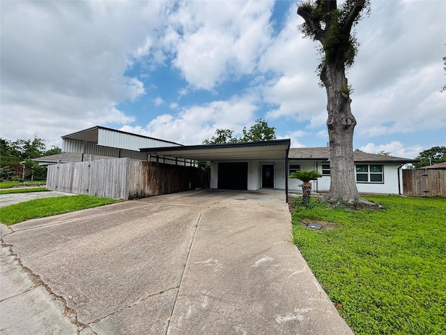 view of front of house featuring fence, a front yard, an attached carport, concrete driveway, and an attached garage