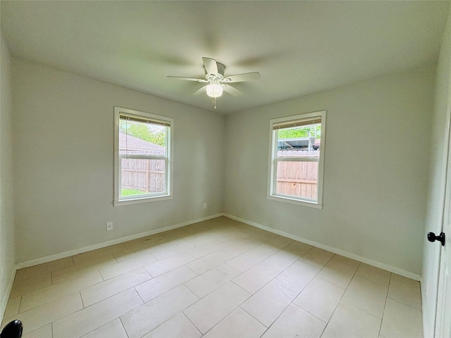 empty room featuring baseboards, ceiling fan, and light tile patterned floors