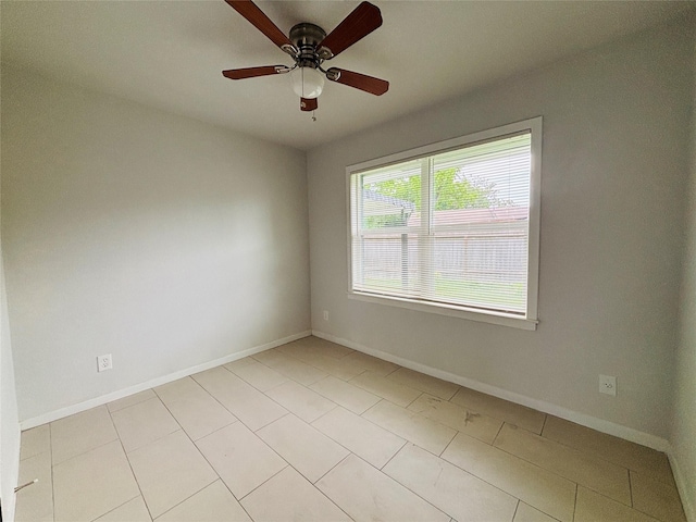 spare room featuring a ceiling fan, baseboards, and light tile patterned floors