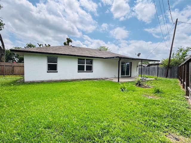 rear view of house featuring a lawn, brick siding, a fenced backyard, and a patio area